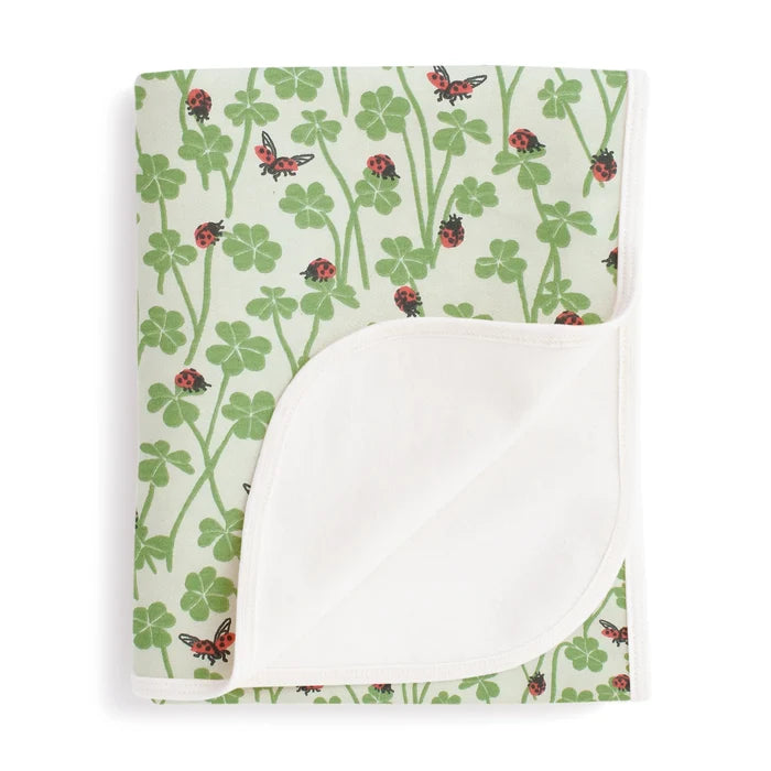 Baby blanket with ladybug and clover pattern on a white background