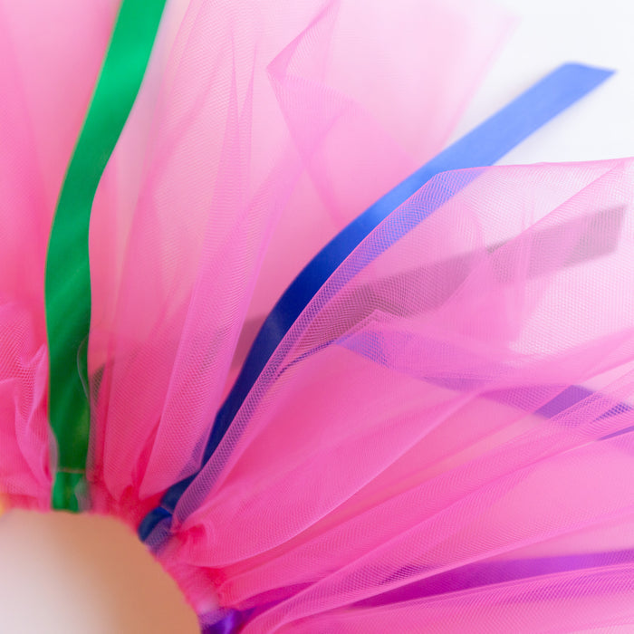 A close-up of the pink tutu with green and blue ribbons