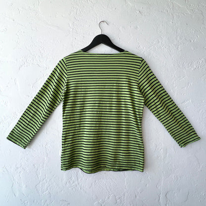 Green and black striped shirt on a hanger against a white wall
