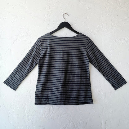 Striped long-sleeve shirt on a hanger against a white wall, viewed from the back