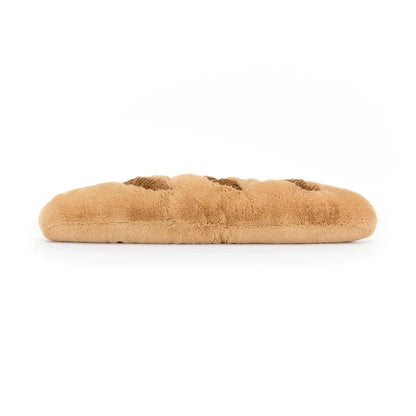 Jellycat Amuseables Baguette — top-down side view of the full-length plush baguette showing the golden-brown textured surface and corduroy score marks, lying flat on a white background
