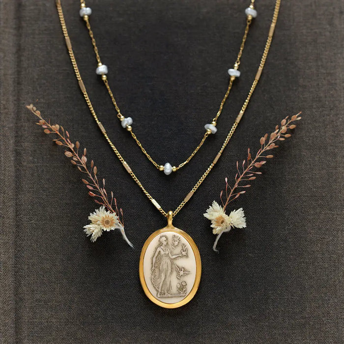 Gold necklace with a pendant and floral elements on a dark fabric background