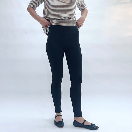 Person wearing black leggings and a striped shirt on a white background