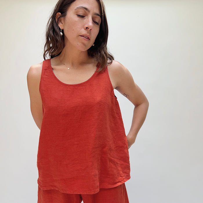A person wearing a red linen tank top and matching pants, standing against a plain background.