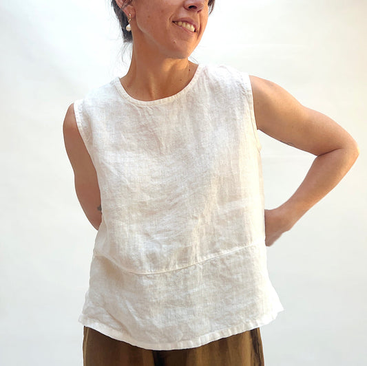Person wearing a white sleeveless top against a plain background