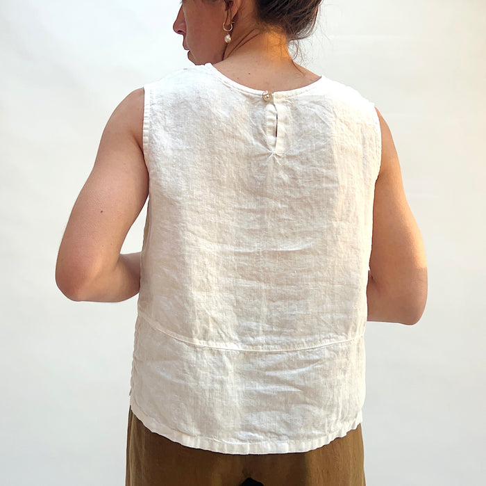 Person wearing a white sleeveless top against a plain background
