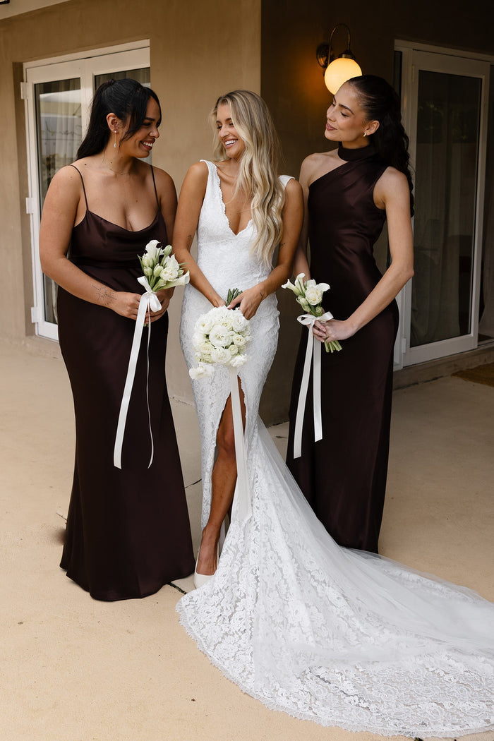 A bridal party wearing brown bridesmaid dresses next to a bride