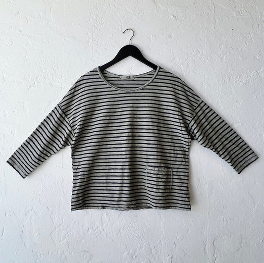 Green and black striped shirt on a hanger against a white wall