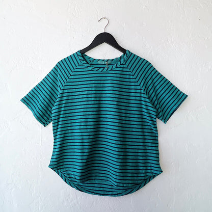 Teal and navy striped shirt on a hanger against a white wall