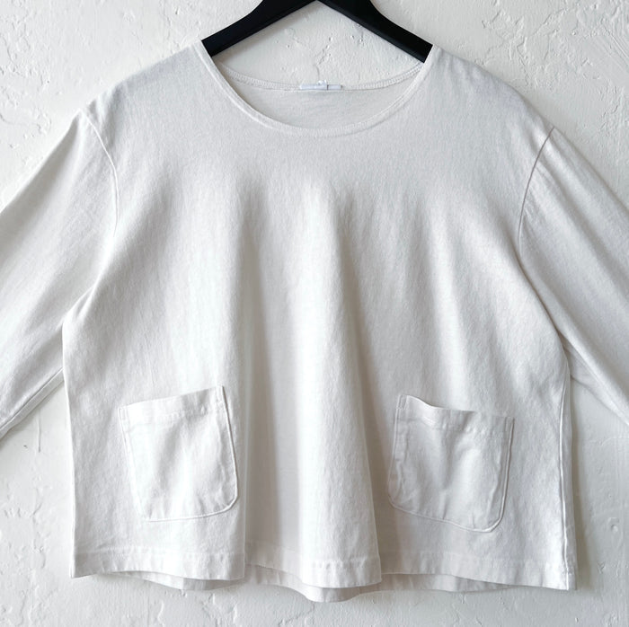 White shirt with two front pockets on a hanger against a white background