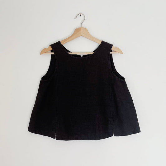 Cropped black linen tank top displayed on a wooden hanger against a white background.