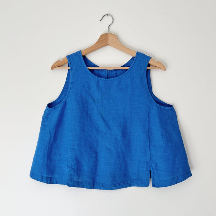 Blue sleeveless tank top on a wooden hanger against a white background