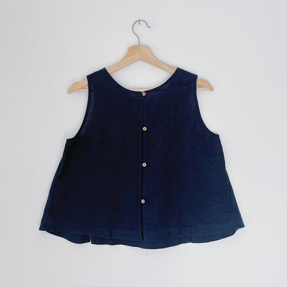 A navy linen tank top with buttons down the back and side slits, displayed on a hanger against a white background.