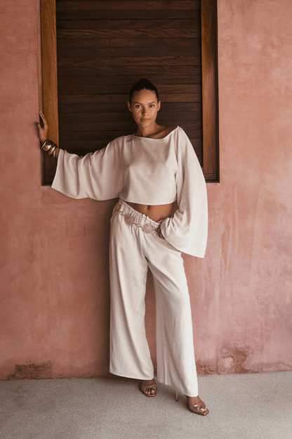 Model wearing the 12th Tribe Clear Breeze White Linen Pants, a best-selling style in a new color featuring a versatile fit that can be worn low or mid-rise, perfect for pairing with crop tops, tanks, or blouses for summer soirées, vacation looks, and effortless warm-weather outfits. Get the full set with the Clear Breeze White Linen Top