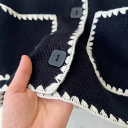 Close-up of a black garment with white trim, held by a hand.