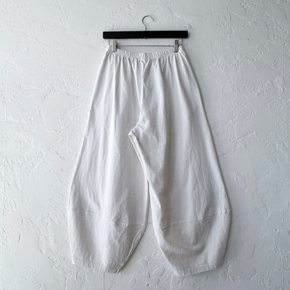 Pacific Cotton cream Oliver pant on hanger, back view showing elastic waistband, voluminous balloon-leg drape, and curved patch hem panels