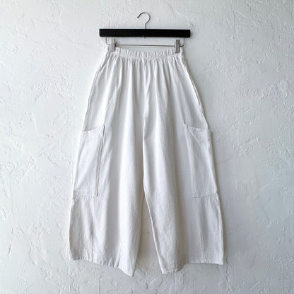 White wide-leg pants on a hanger against a white wall