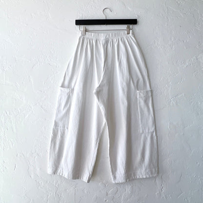 White pants hanging on a hanger against a white wall