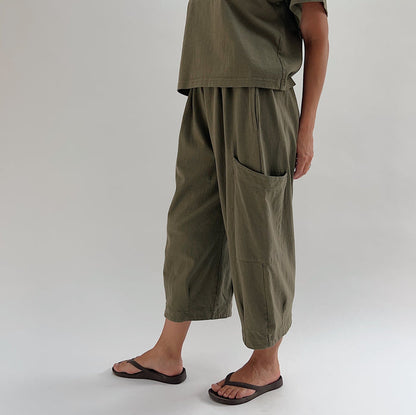 Side view of model wearing Bryn Walker jasper Pasha pant, showing large patch pocket detail, wide-leg drape, and banded hem at ankle