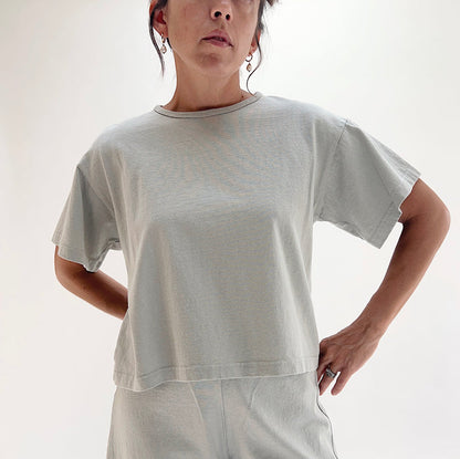 Close front view of model wearing Pacific Cotton orlaya crop crew tee, showing ribbed crew neckline, short sleeves, boxy cropped fit, and sage green color