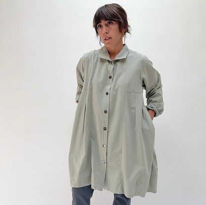 Front view of model wearing Eleven Stitch artichoke darted coat buttoned closed, showing point collar, button placket, front patch pockets, and full coat length