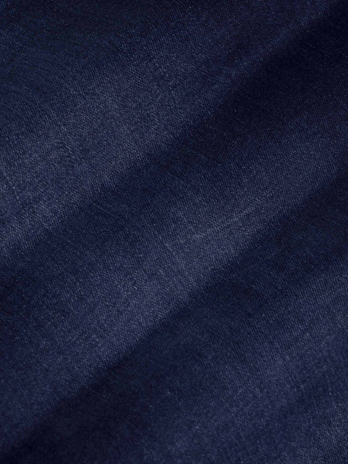 Close-up of dark navy denim fabric texture showing smooth weave and slight fade – Wam Denim.