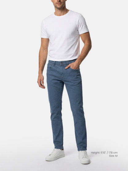 Model wearing slim fit blue men’s jeans with white t-shirt.