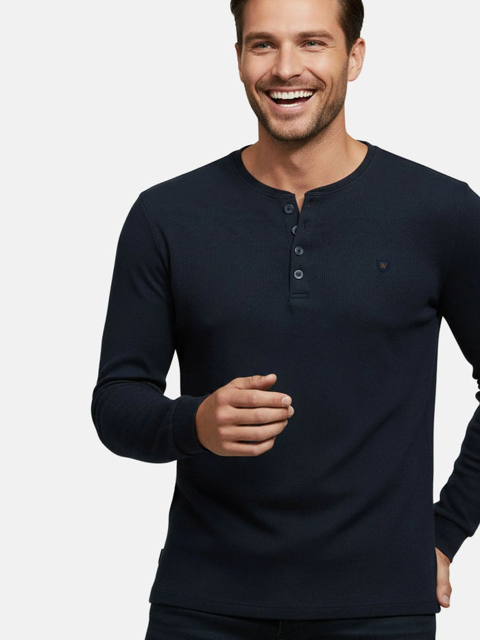 Close-up of model wearing navy long-sleeve Zest sweater with buttoned neckline.