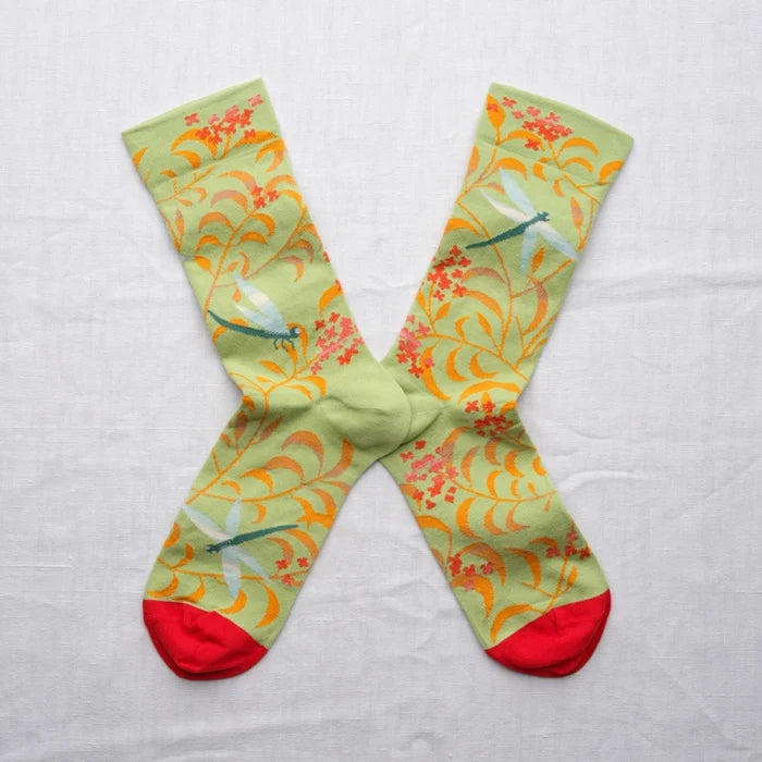 Colorful socks with floral and dragonfly pattern on a light gray background