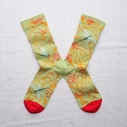 Colorful socks with floral and dragonfly pattern on a light gray background