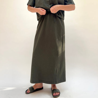 Person wearing a long dark green skirt on a white background