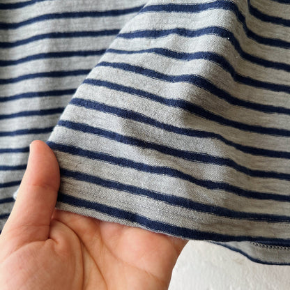 Close-up of a hand holding striped fabric with blue and gray horizontal lines.