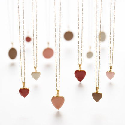 6 heart-shaped necklaces dangling against a white backdrop in shades of pink and white with gold chains