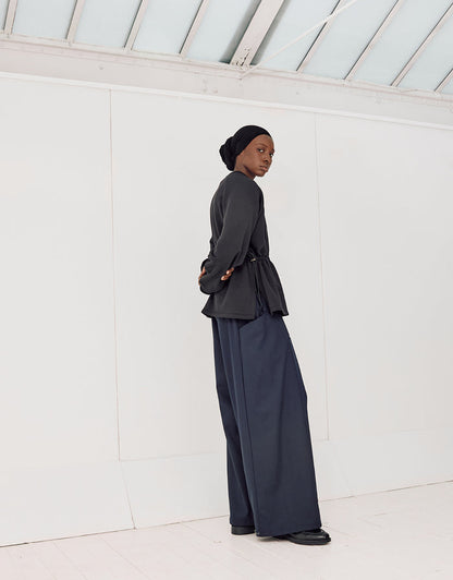 Model wearing navy boyfriend fit flared pants paired with a black minimalist top and headscarf, showcasing understated elegance and high-quality craftsmanship.