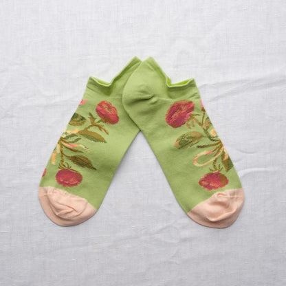 Green ankle socks with floral patterns on a light gray background