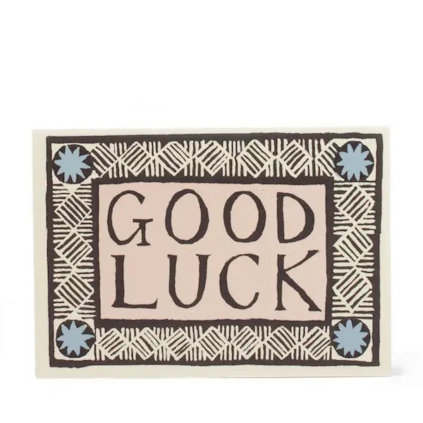 A greeting card with 'Good Luck' text in a decorative font, surrounded by a geometric pattern.