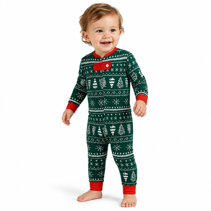 Smiling baby modeling green Christmas pajamas with white festive print and red trim on a white background.