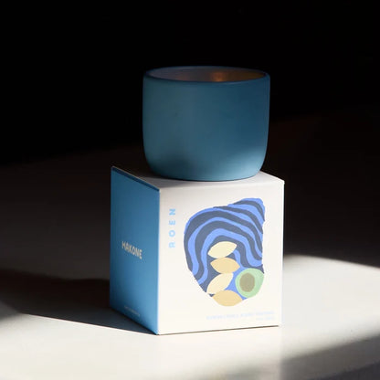 Blue candle on a white box with a blue label against a dark background