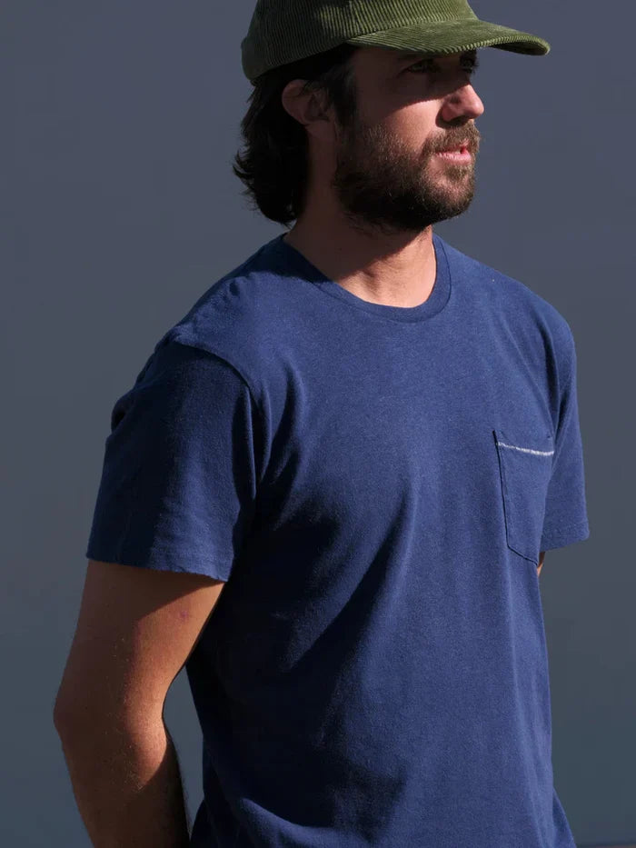 Man wearing a blue t-shirt and green cap against a dark background