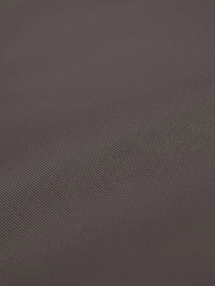 Close-up of light brown shirt fabric with smooth texture and fine weave.