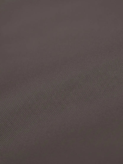 Close-up of light brown shirt fabric with smooth texture and fine weave.
