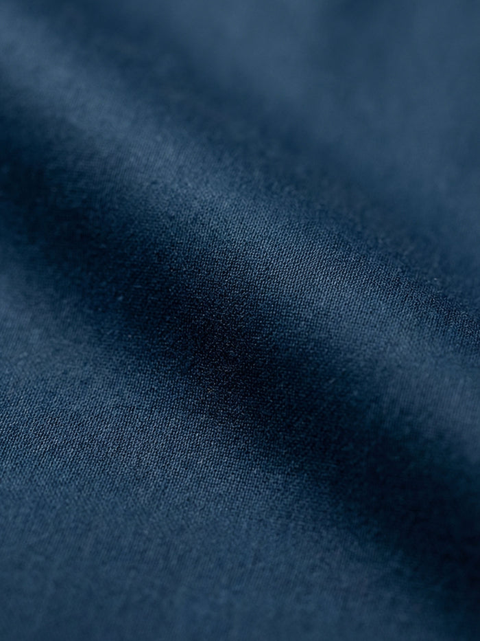 Close-up of petrol blue shirt fabric showing smooth texture and premium woven material.
