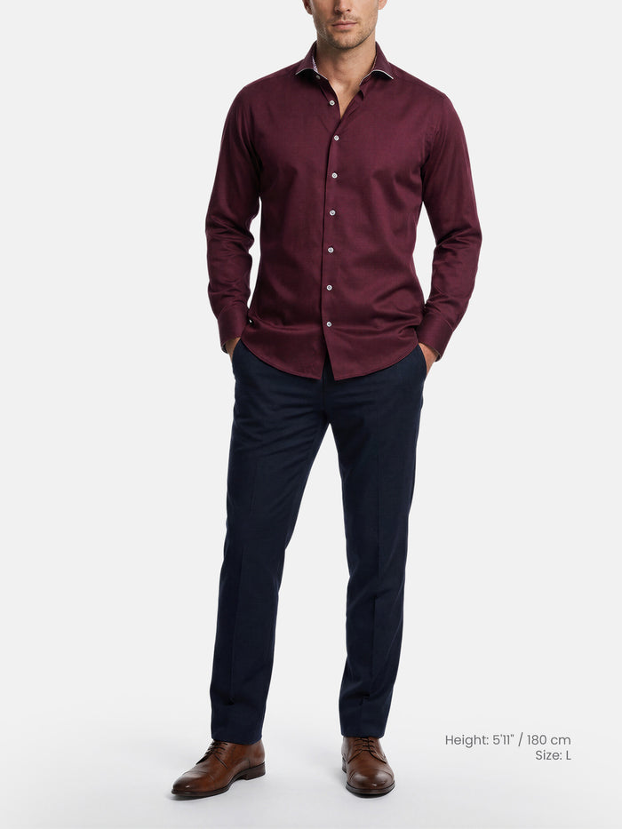 Model wearing dark red men’s dress shirt styled with navy trousers and leather shoes