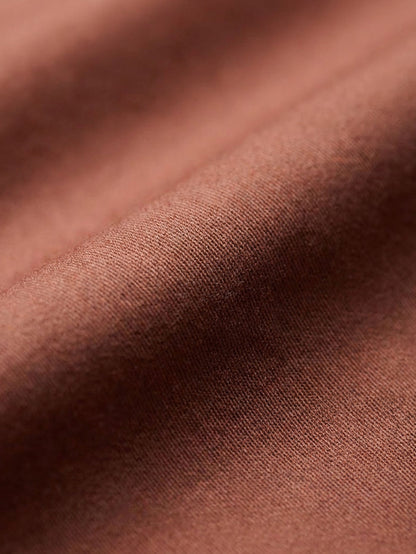 Close-up of light brown men’s shirt fabric showing smooth texture and premium weave