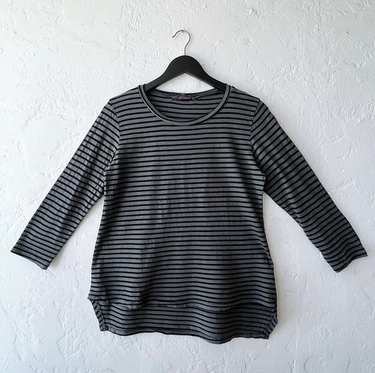 Black and gray striped long-sleeve shirt on a hanger against a white wall
