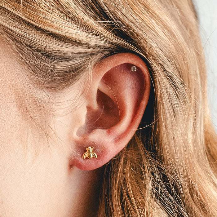 Close-up of a person's ear wearing bumblebee gold earring
