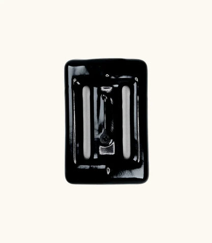 Black rubber-coated Lava Rock dive weight with slotted openings, photographed from above against a white background.