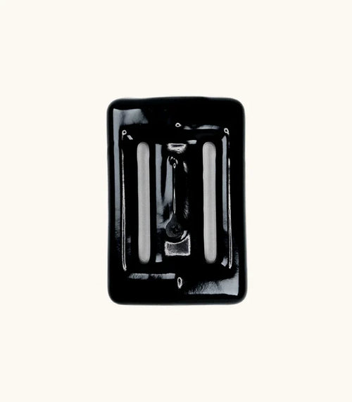 Black rubber-coated Lava Rock dive weight with slotted openings, photographed from above against a white background.