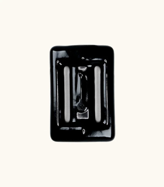 Black rubber-coated Lava Rock dive weight with slotted openings, photographed from above against a white background.