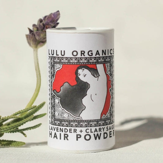 Lulu Organics Lavender and Clary Sage Hair Powder Shampoo 1oz white cylindrical container with illustrated label, styled with a fresh lavender sprig on a cream background